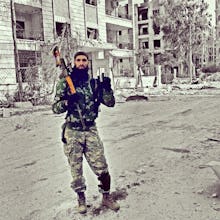 A soldier from Syria's Civil War posing with a rifle in the middle of a street