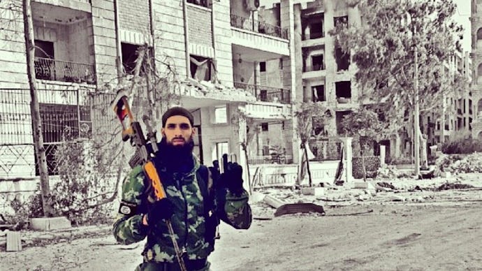 A soldier from Syria's Civil War posing with a rifle in the middle of a street