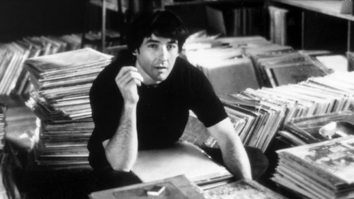 Film still from "High Fidelity", a man sitting next to various stacks of books
