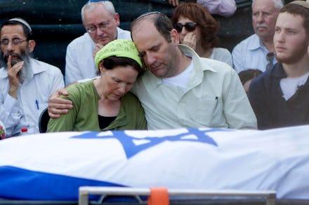 Two parents comforting each other after the death of their murdered teen
