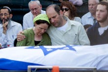 Two parents comforting each other after the death of their murdered teen