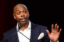 Dave Chappelle in a formal suit during a performance