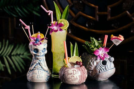 A variety of different tiki style cocktails on a reflective black table