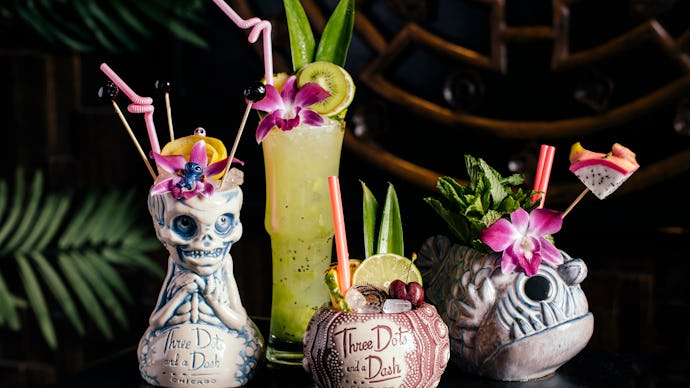 A variety of different tiki style cocktails on a reflective black table