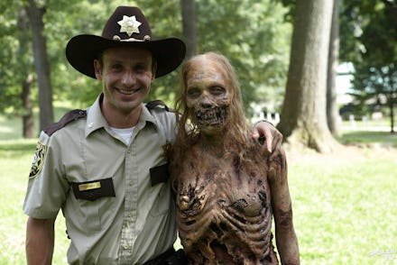 A policeman posing with a scary skeleton in a park