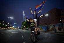 Two boys riding on a bicycle down a road