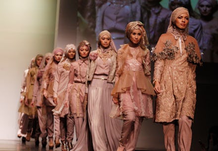 Models walking on the runway wearing hijabs and modest clothing in beige and grey tones