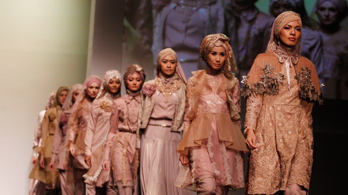 Models walking on the runway wearing hijabs and modest clothing in beige and grey tones
