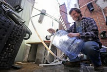 A Virginian man collecting water from a hose into a cannister 