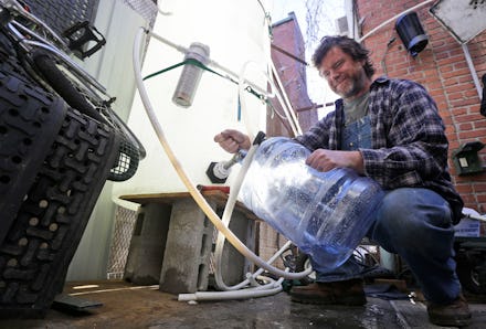 A Virginian man collecting water from a hose into a cannister