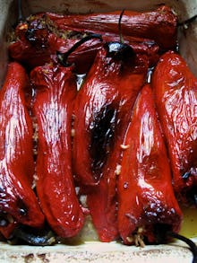 Roasted red peppers in a tray with olive oil and garlic over them