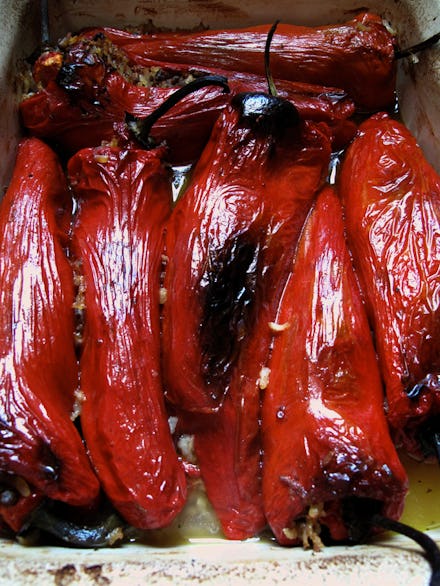 Roasted red peppers in a tray with olive oil and garlic over them