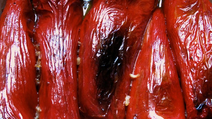 Roasted red peppers in a tray with olive oil and garlic over them