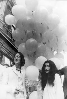 John Lennon and Yoko Ono posing and holding dozens of balloons