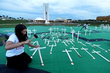 A woman making a white wooden cross for a person died protecting land from agribusiness.