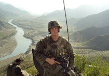 A marine corps soldier standing in front of a mountain range holding his rifle