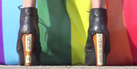 A person in heels with the text 'RUN 4 SHELTER' in front of a LGBTQ Youth flag