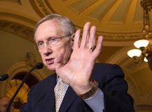 A politician with his hand raised towards the camera in order to block the picture being taken