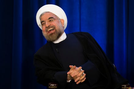Hassan Rouhani sitting in a chair and laughing