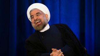 Hassan Rouhani sitting in a chair and laughing
