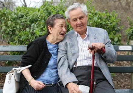 An old couple hugging on a park bench in New York City