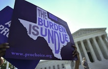 Protestors holding signs of texas with the words the burden is undue