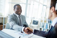 Two men in suits shake hands after a successful interview