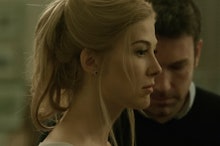 Rosamund Pike looking forward with Ben Affleck in the back looking down in Gone Girl