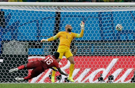Silvester Varela scoring a goal, falling on the floor while the U.S, goalkeeper is trying to catch t...
