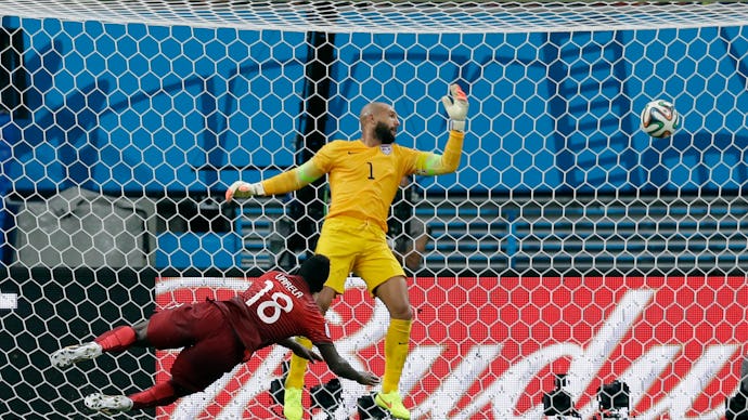 Silvester Varela scoring a goal, falling on the floor while the U.S, goalkeeper is trying to catch t...