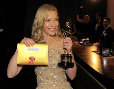 Cate Blanchett in a sheer bedazzled dress with the Oscar she received for her role in Blue Jasmine