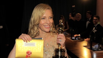Cate Blanchett in a sheer bedazzled dress with the Oscar she received for her role in Blue Jasmine