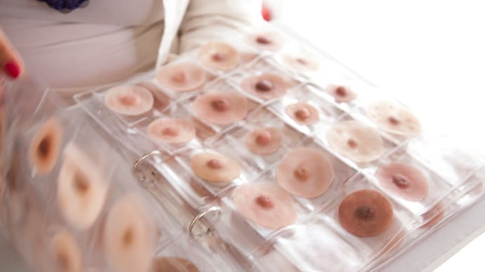 A woman holding an example box with fake nipples for women who had a masectomy