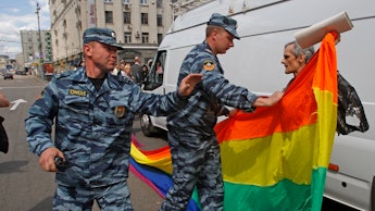 Russian officers taking a LGBT flag from a man holding it on a street