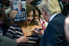 Donald Trump signing a female fan's chest