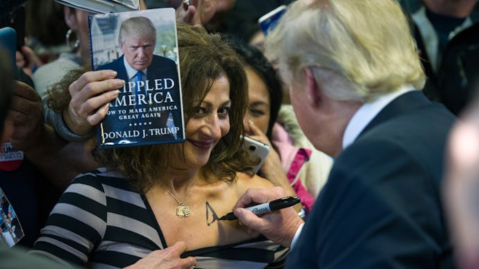 Donald Trump signing a female fan's chest
