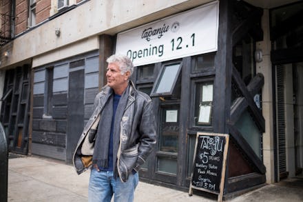 Anthony Bourdain walking on the streets of new york in front of a newly opening restaurant