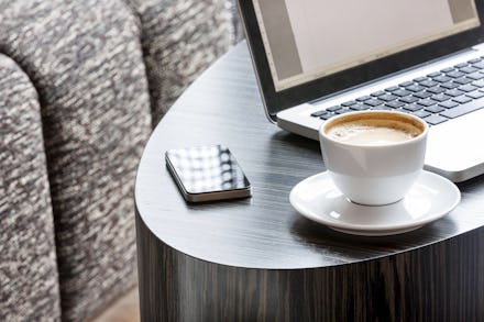 A coffee cup, laptop and iPhone on a coffee table 