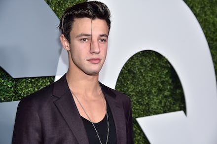 Cameron Dallas in a black blazer and black low-cut t-shirt 