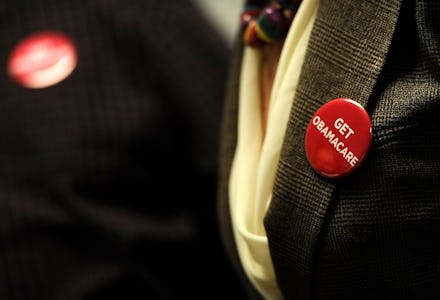 A person in a suit with a get obamacare pin on their lapel