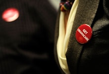 A person in a suit with a get obamacare pin on their lapel