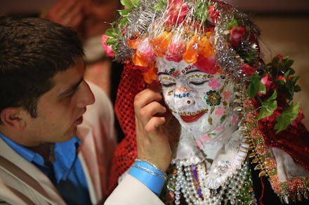 A bride's face being painted white and decorated with colorful sequins in Robnovo, Bulgaria