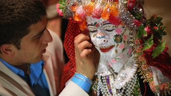 A bride's face being painted white and decorated with colorful sequins in Robnovo, Bulgaria