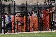 Prisoners behind the fence at the yard of Guantánamo Bay with a police officer 