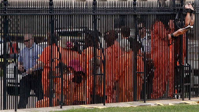Prisoners behind the fence at the yard of Guantánamo Bay with a police officer 