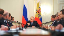 Putin talking at a meeting while sitting at a table top