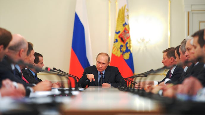 Putin talking at a meeting while sitting at a table top