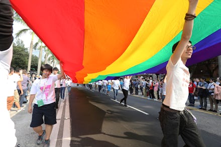 People walking, holding a large pride flag