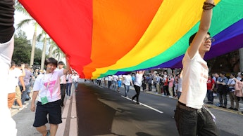 People walking, holding a large pride flag 