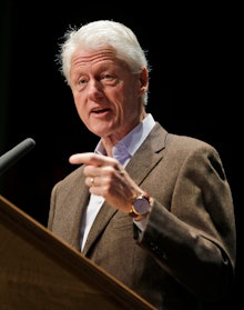 Bill Clinton giving his opinions on Obamacare at a podium with a microphone, pointing his index fing...